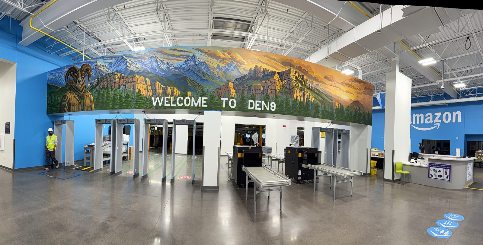 A panoramic mural of the Colorado front range at sunrise above the security screening lanes at Amazon DEN9