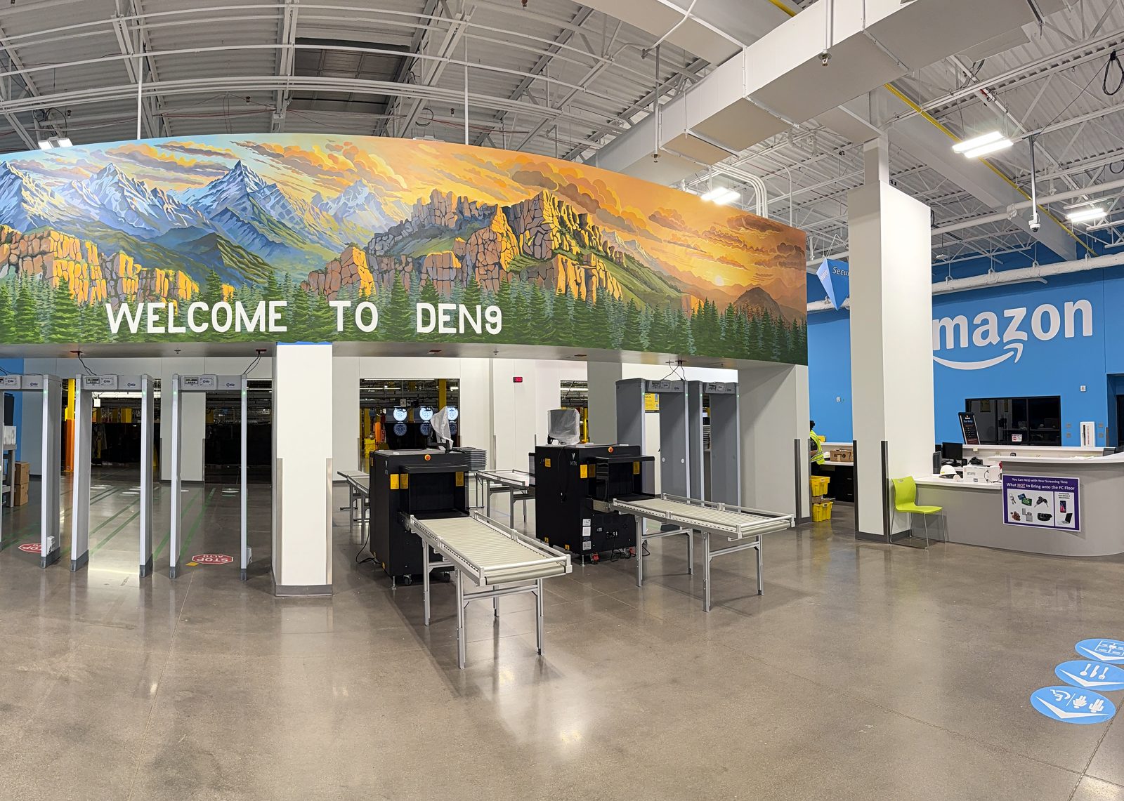 A wide mural above the screening lanes inside a fulfillment center