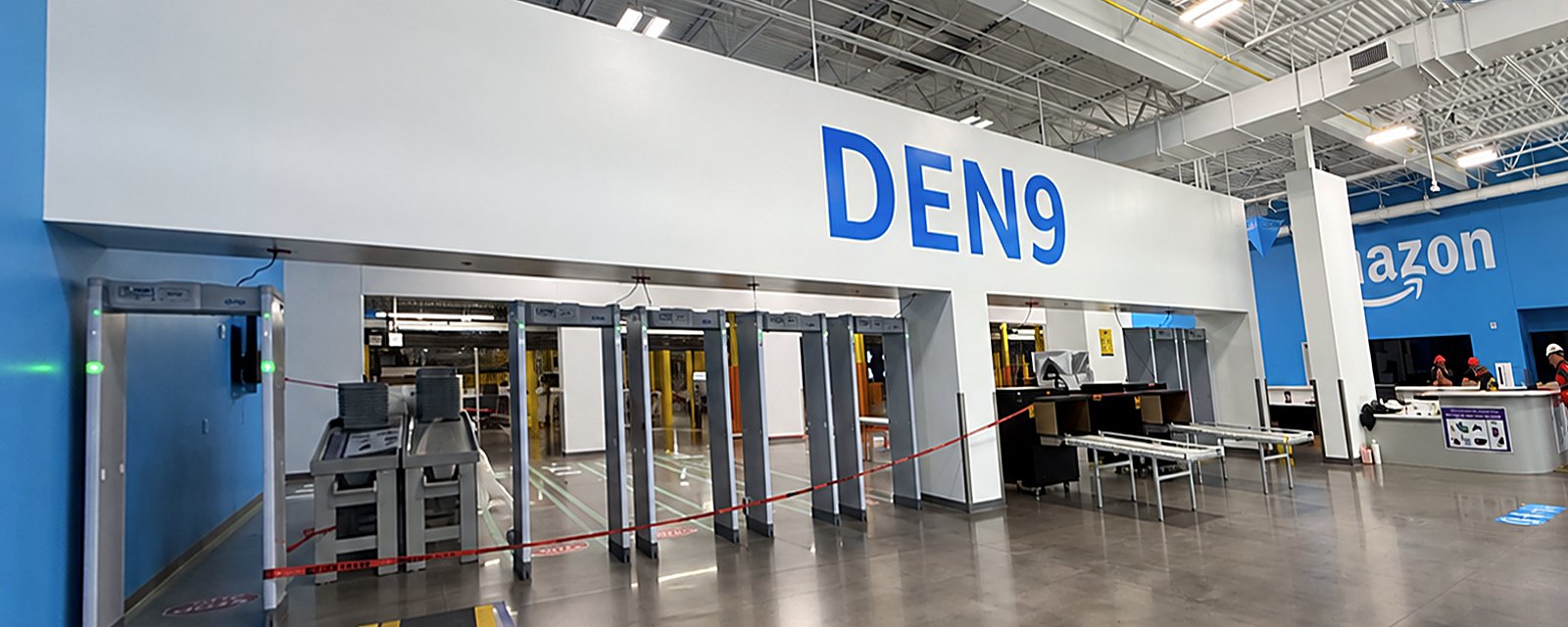 The blank wall above the security screening lanes at Amazon DEN9 in Loveland, before painting