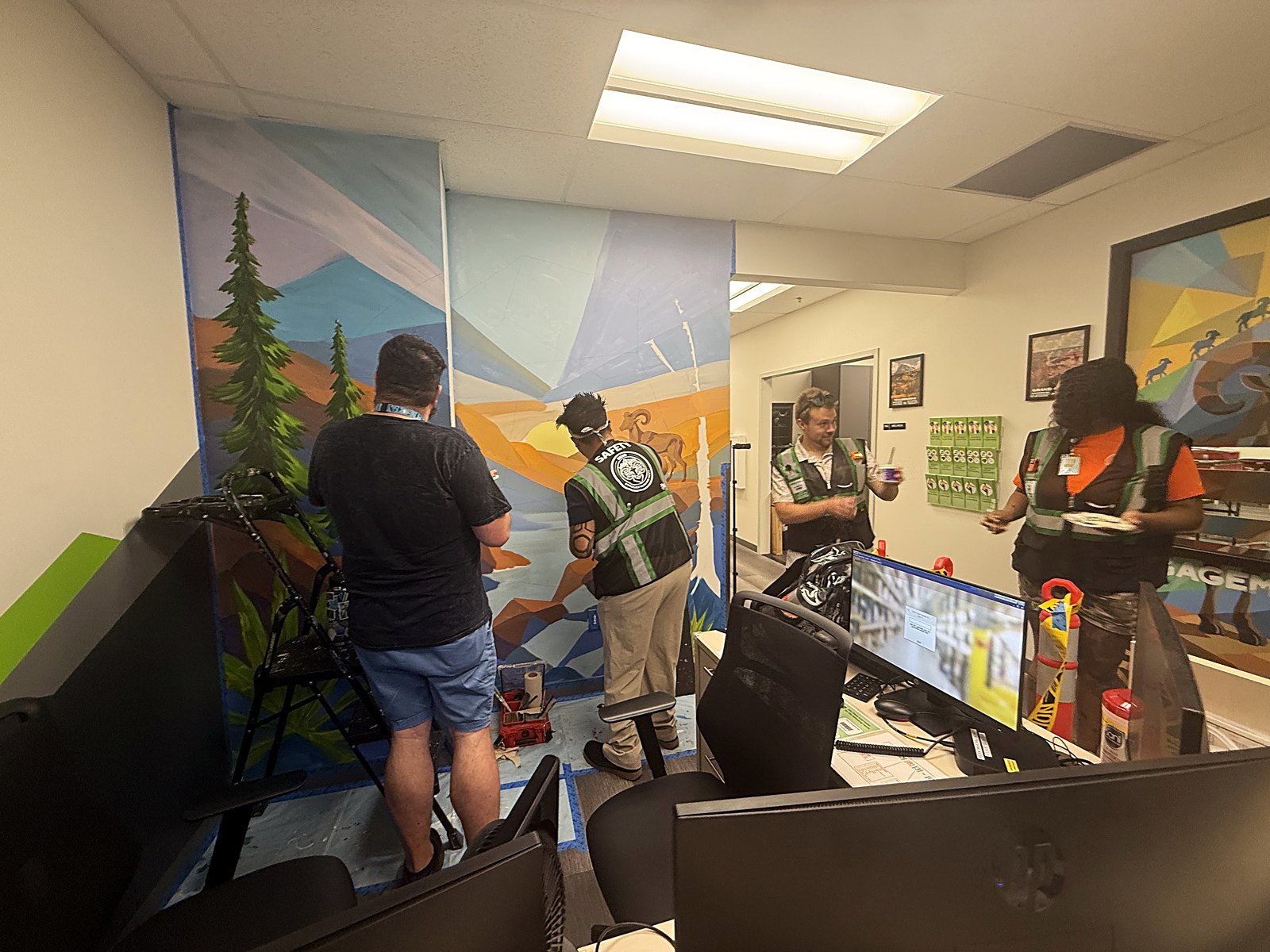 Wellness center staff painting shapes into the mural alongside the artist during the installation
