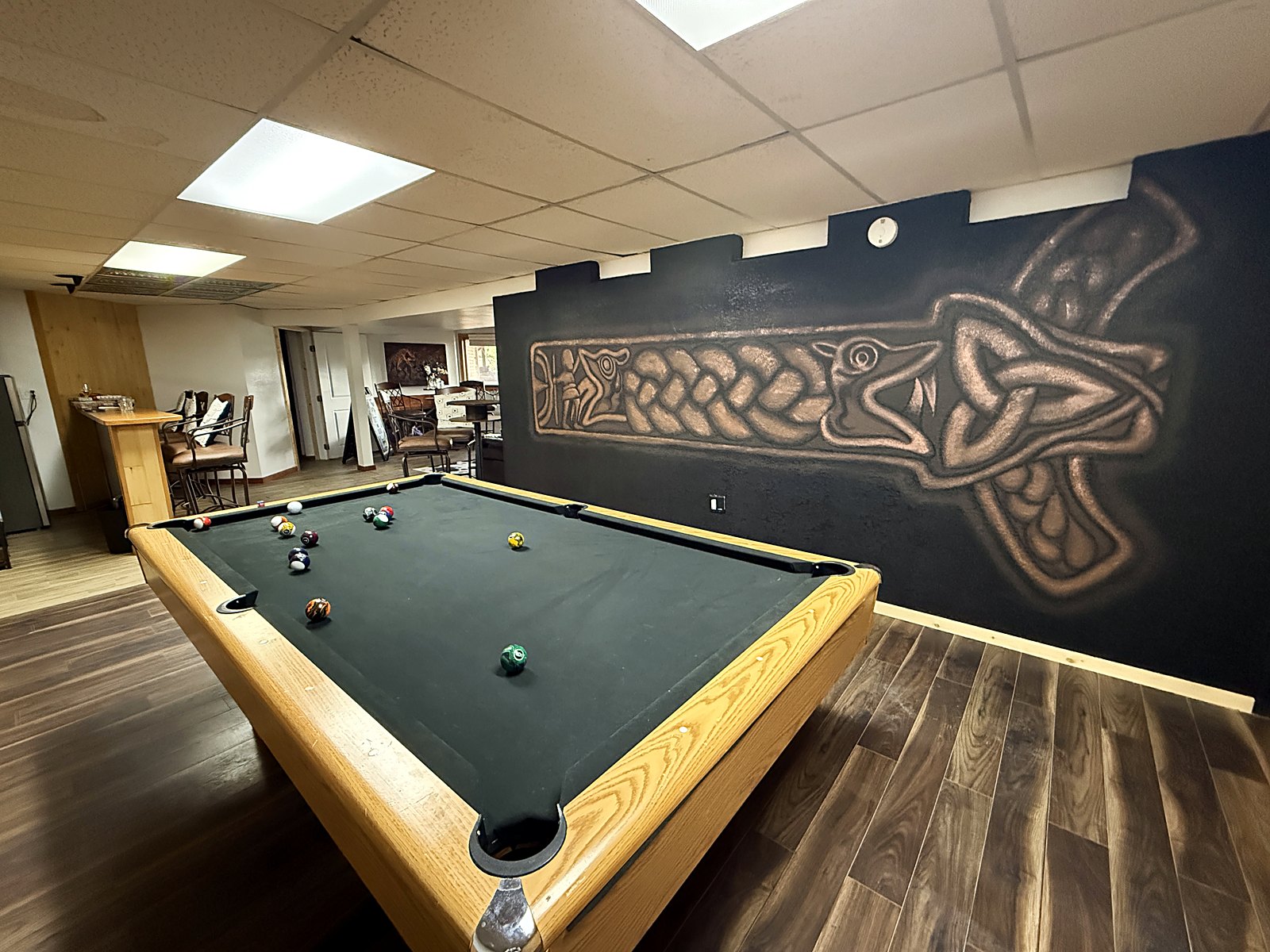 Celtic and Norse knotwork painted in copper tones across a dark wall above a pool table