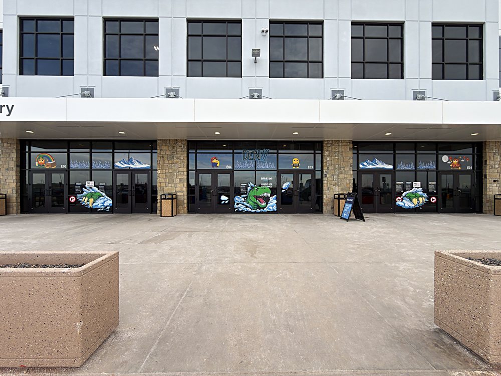 Hand-painted seasonal window display on the entrance glazing of an Amazon fulfillment center in Colorado, february 2026. the full entrance, seen from the lot