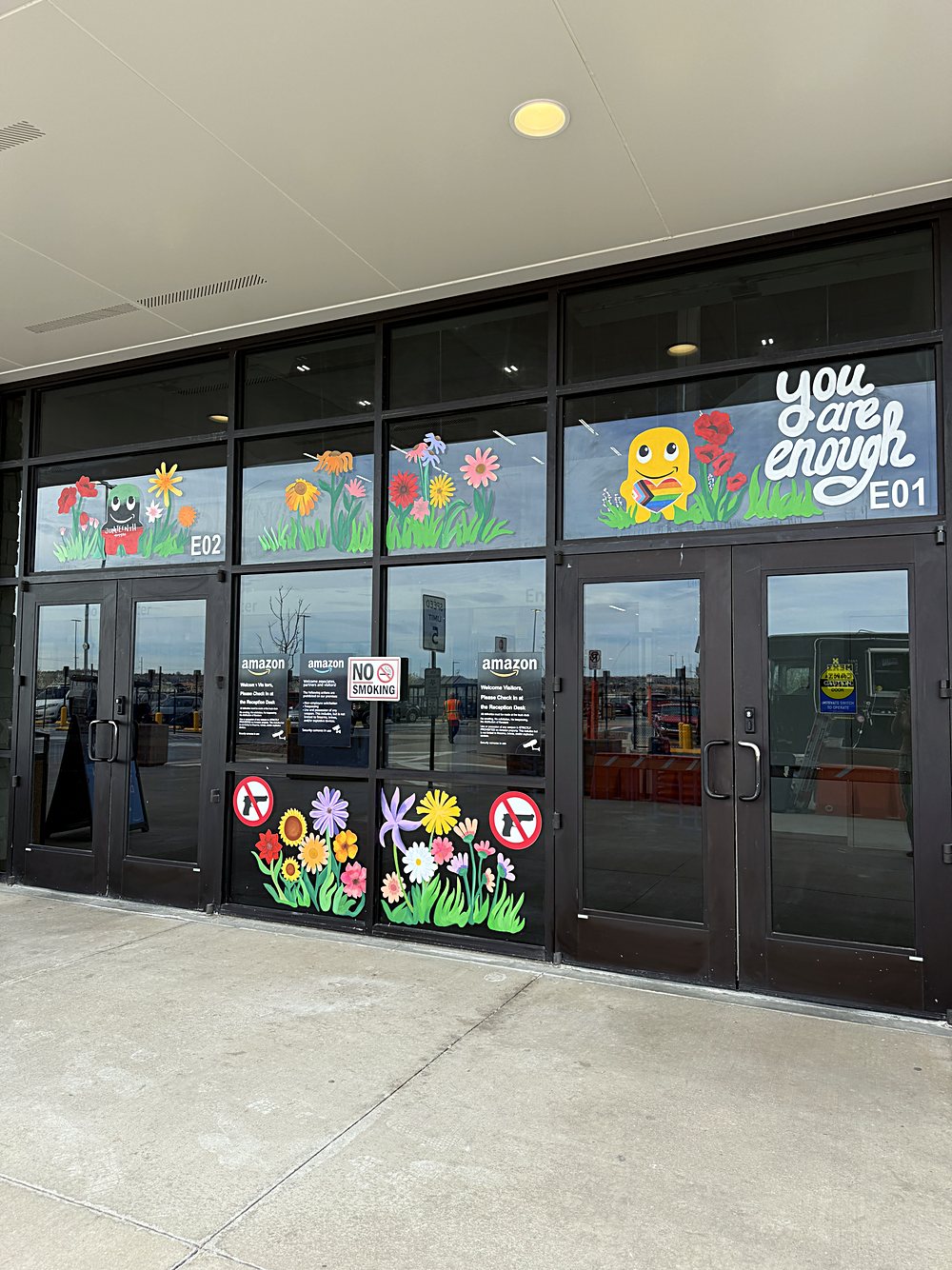 Hand-painted seasonal window display on the entrance glazing of an Amazon fulfillment center in Colorado, march 2026. spring planting along the lower panels