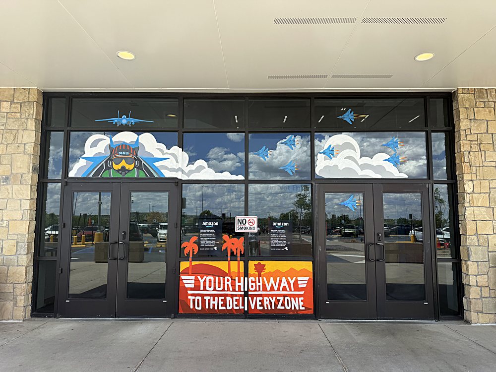 Hand-painted seasonal window display on the entrance glazing of an Amazon fulfillment center in Colorado, may 2026. highway to the delivery zone
