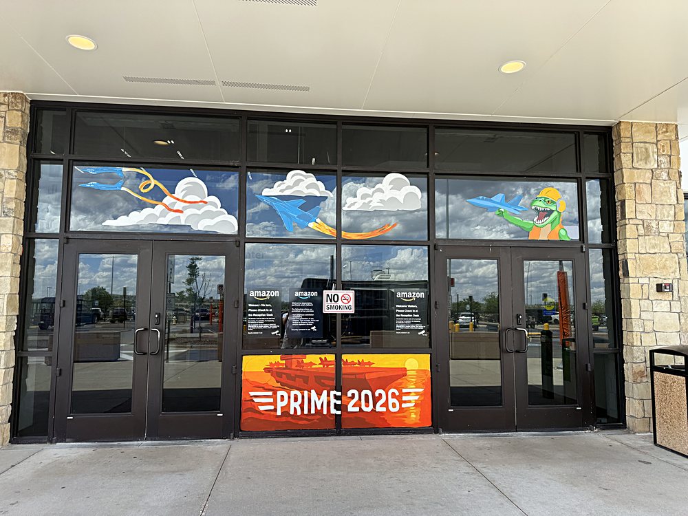 Hand-painted seasonal window display on the entrance glazing of an Amazon fulfillment center in Colorado, may 2026. prime 2026, painted into a sunset