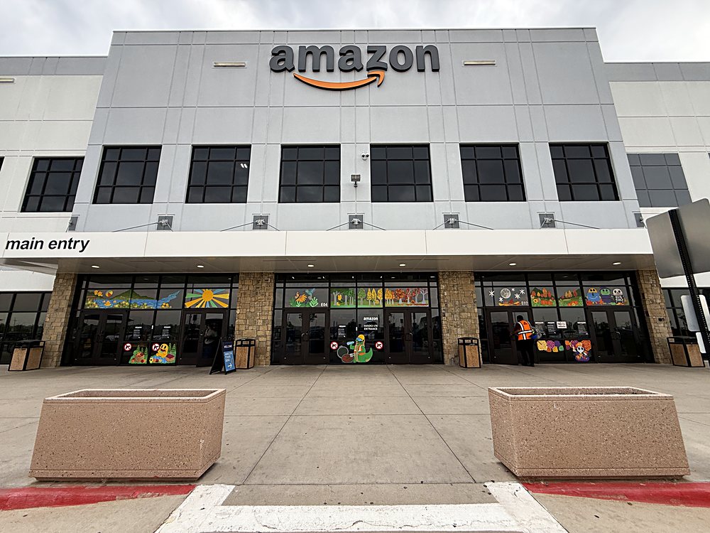 Hand-painted seasonal window display on the entrance glazing of an Amazon fulfillment center in Colorado, august 2026. the finished entrance from the parking lot