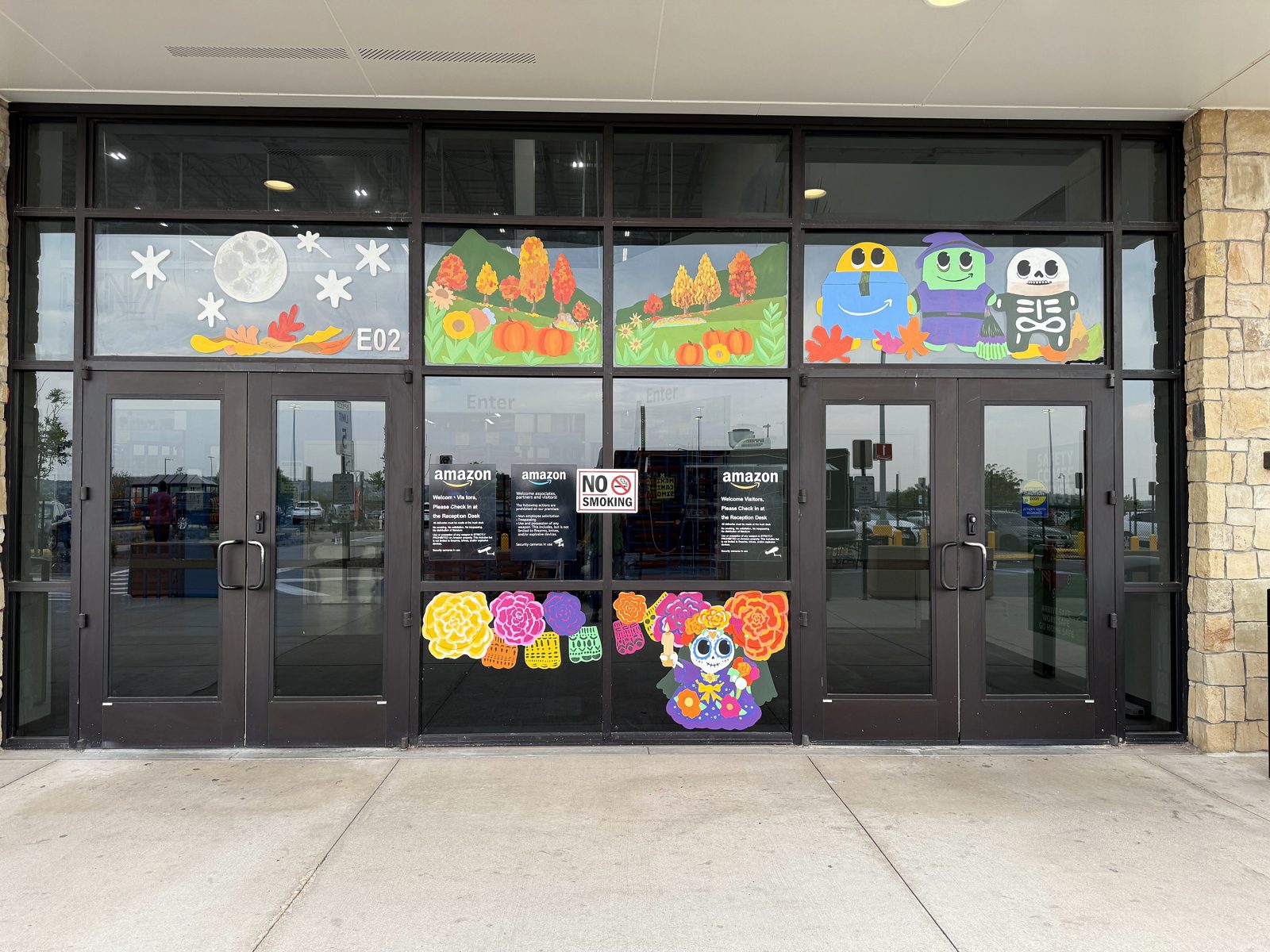 Seasonal window display painted on entrance glazing with fall and Dia de Muertos panels